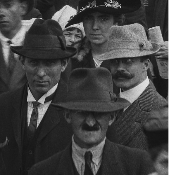 Three odd looking men in crowd.