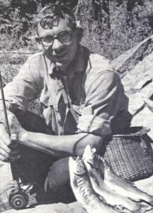a young man crouching by three fish he caught using a fly rod